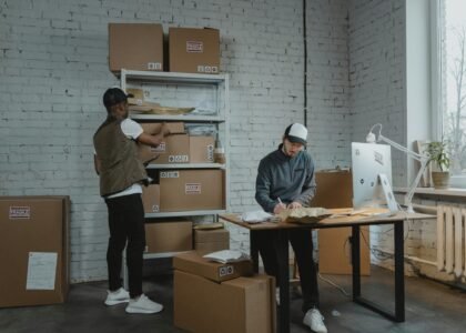 Two workers handling packages and organizing stock in a warehouse setting.